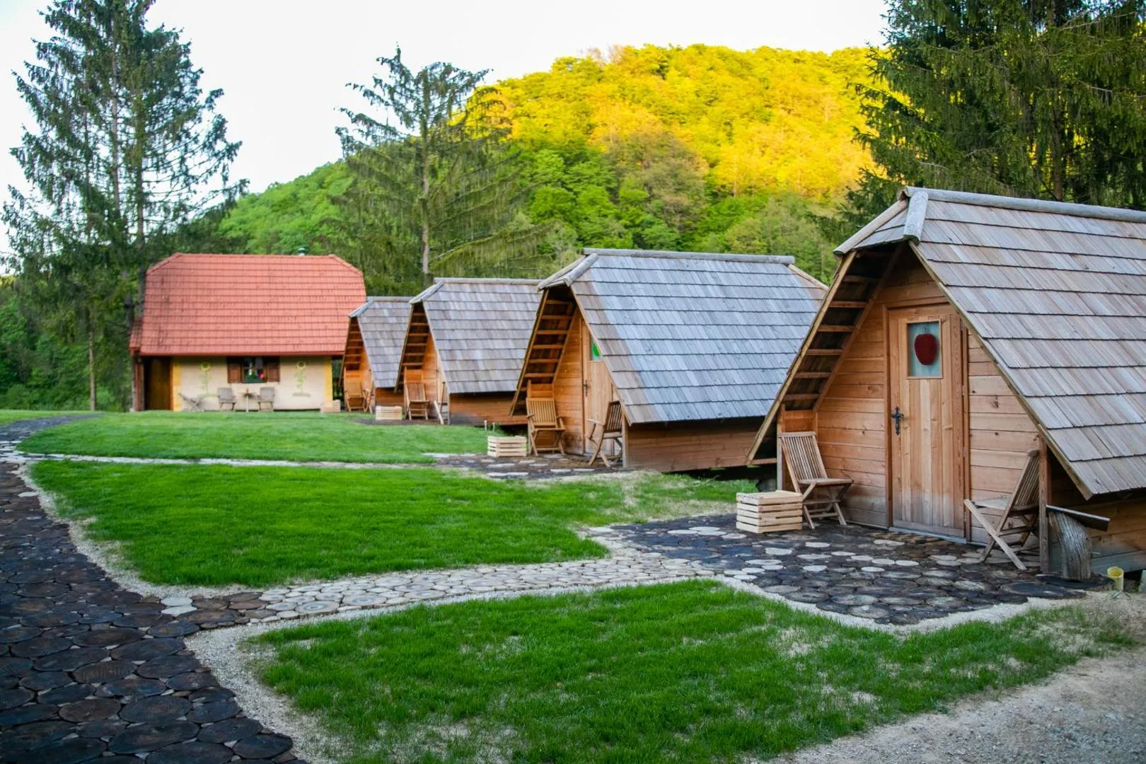 Zunanjost: vrsta macesnovih glamping hišk med drevesi.