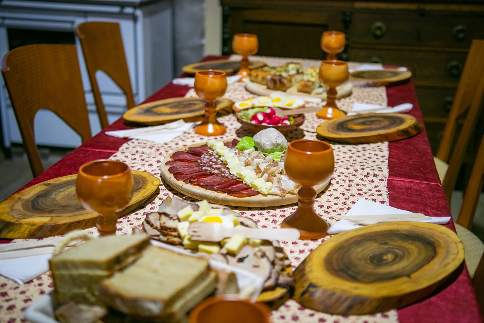 Local breakfast on a long table — cured meats, cheeses, eggs, fresh bread, jams.